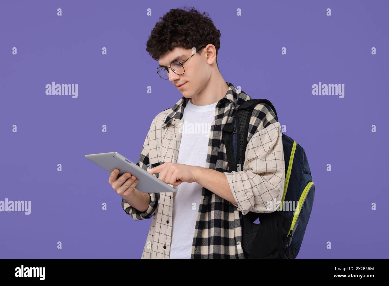 Porträt des Schülers mit Rucksack und Tablet auf violettem Hintergrund Stockfoto