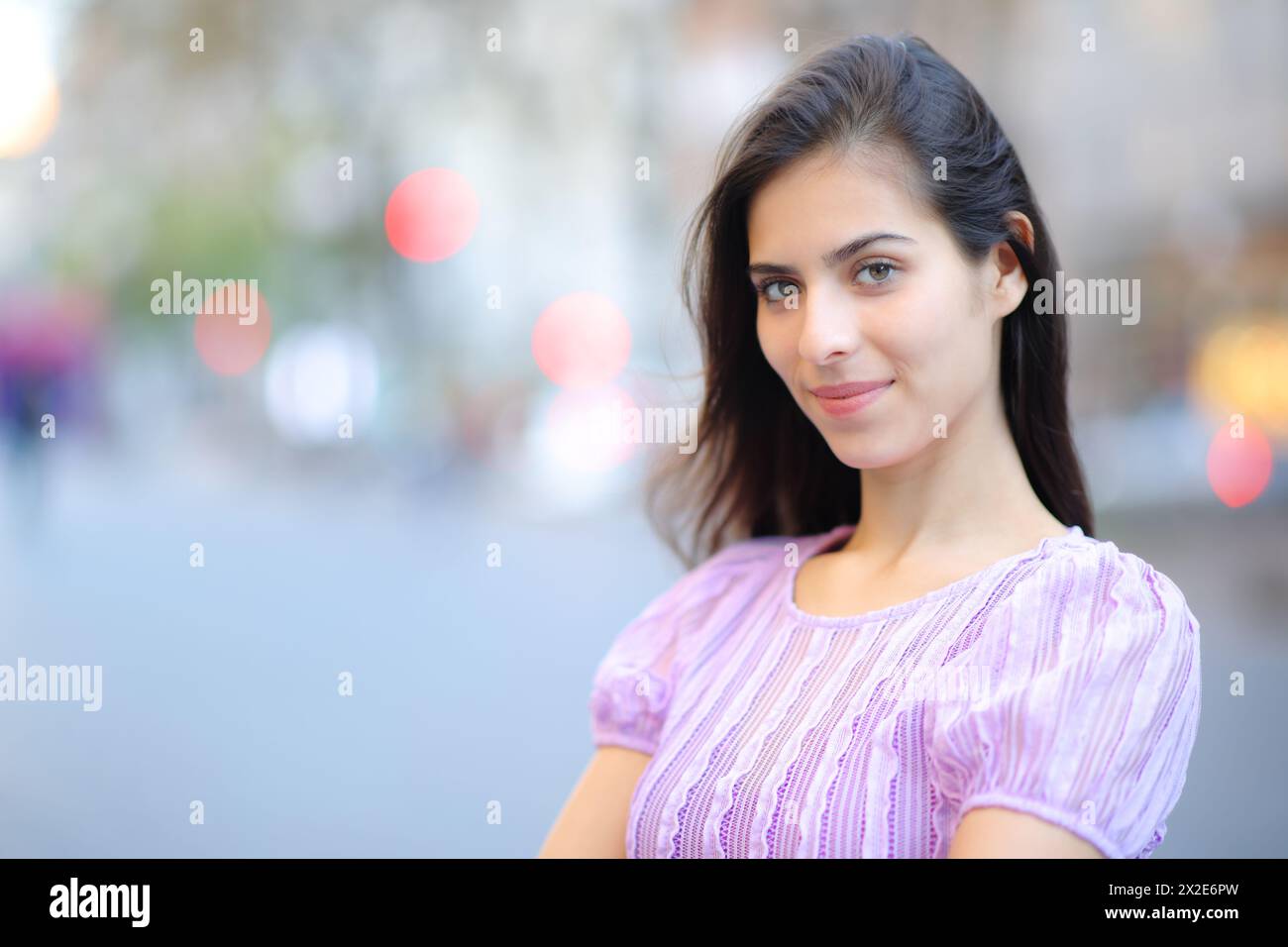Eine zufriedene Schönheitsfrau posiert und sieht dich auf der Straße an Stockfoto