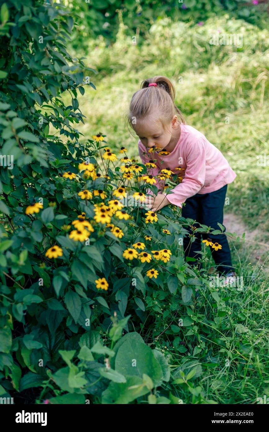 Kleines Mädchen mit Blumen auf dem Land im Hinterhof Stockfoto