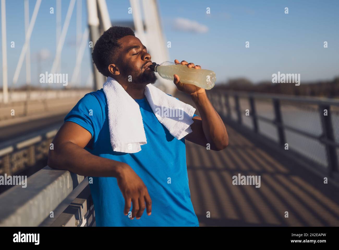 Porträt eines jungen afroamerikanischen Mannes, der nach dem Joggen Wasser trinkt und sich entspannt. Stockfoto