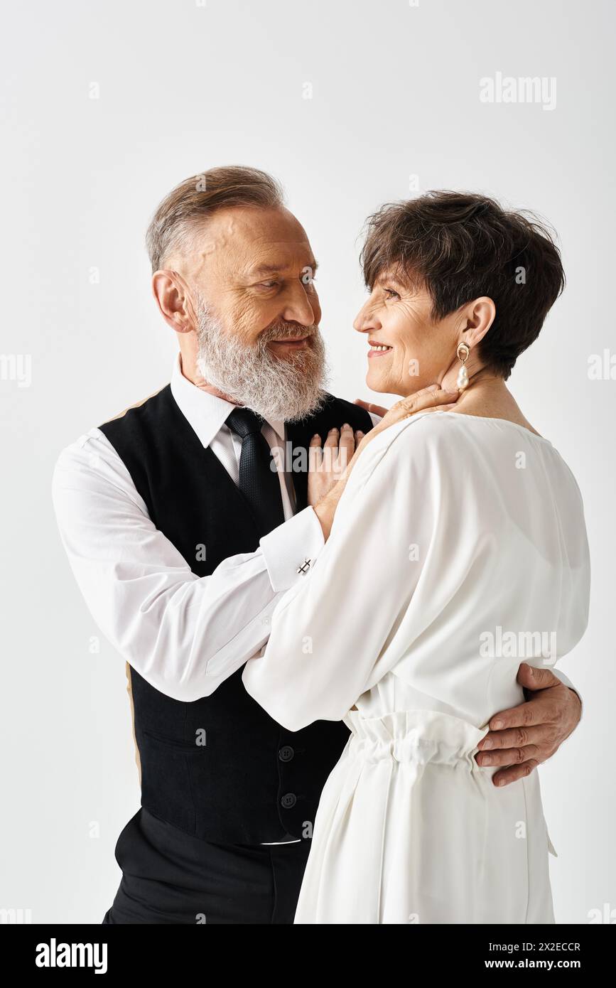 Eine Braut und ein Bräutigam mittleren Alters in Hochzeitskleidern feiert ihren besonderen Tag in einem Studio. Stockfoto