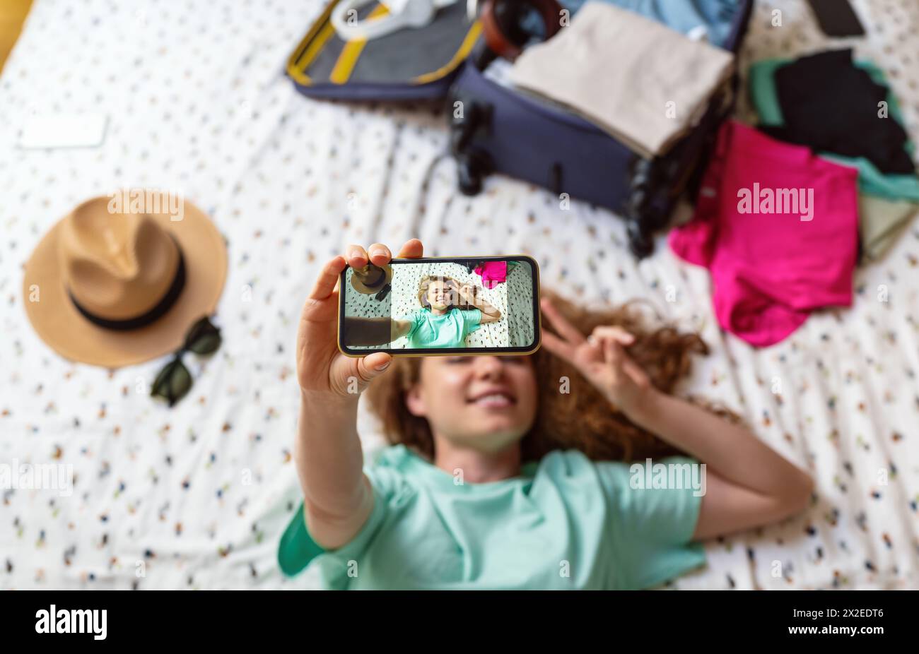 Frau, die im Hotel liegt und ein Selfie macht. Fotonachrichten an Freunde von Reisen. Stockfoto