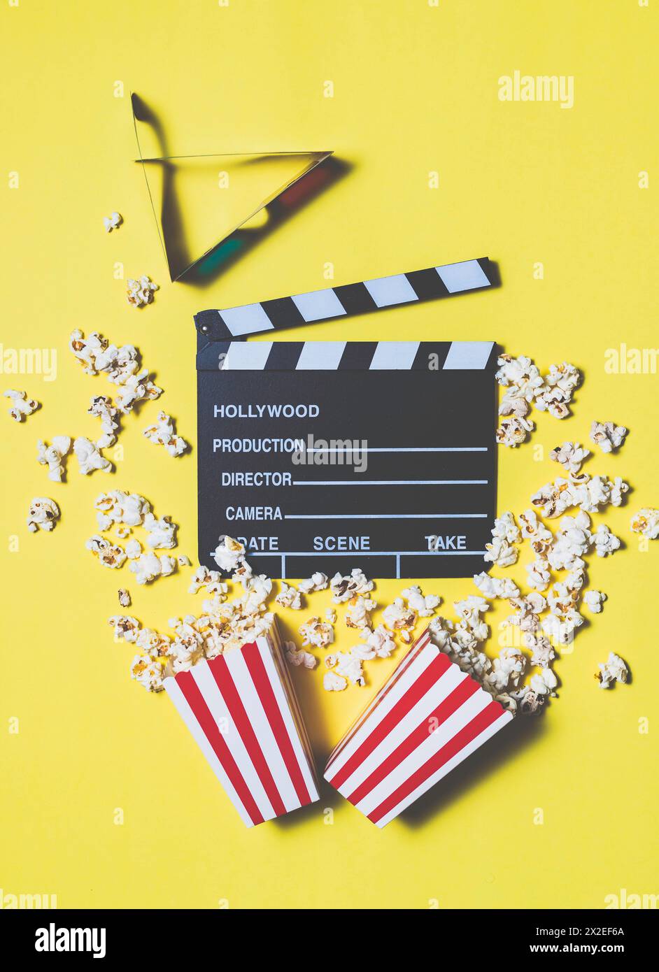 Filmklapperboard und Popcorn auf gelbem Hintergrund. Konzept für Kino, Unterhaltung, audiovisuelle Medien Stockfoto