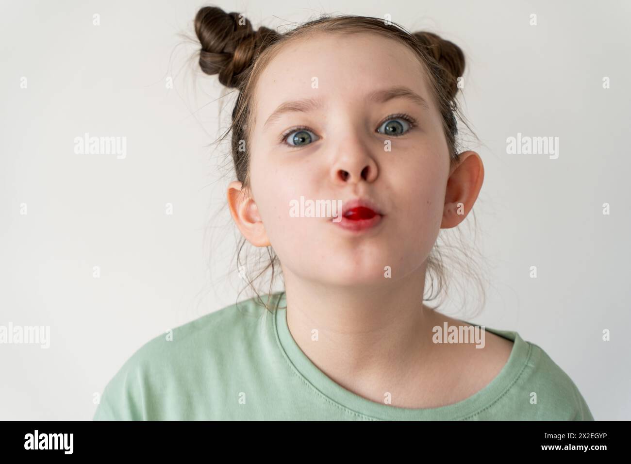 Lustiges kleines Mädchen, das herumspielt, während sie einen roten Lutscher im Mund hält. Hochwertige Fotos Stockfoto