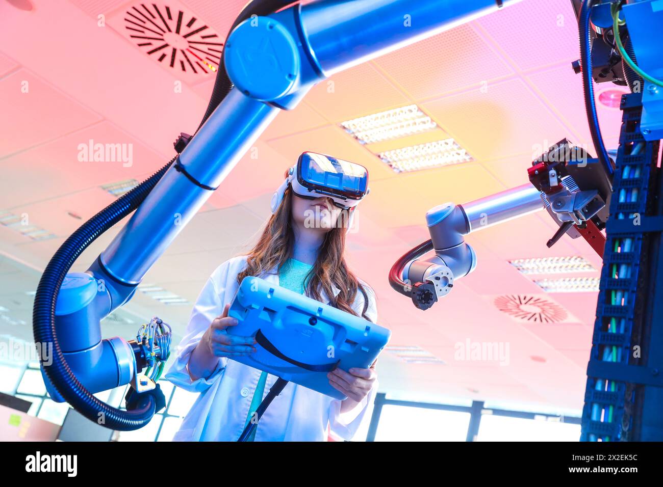 Roboterarm mit künstlichem Sehen, Forscher mit Virtual-Reality-Brille, VR, humanoider Roboter für Montageaufgaben in der Automobilindustrie in Zusammenarbeit mit pe Stockfoto