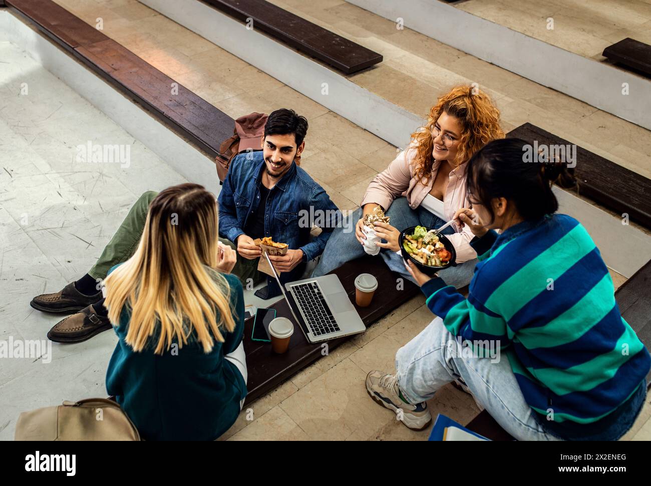 Gruppe von Studenten, die auf dem Campus sitzen und eine Mittagsbremse haben. Stockfoto