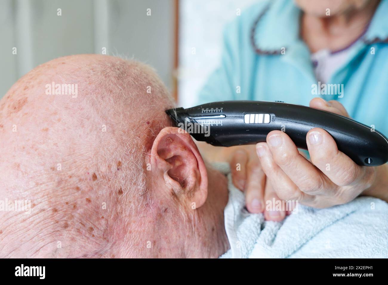 Nahaufnahme eines älteren Paares, das zu Hause Haare schneidet. Der ältere Mann ist kahl. Stockfoto