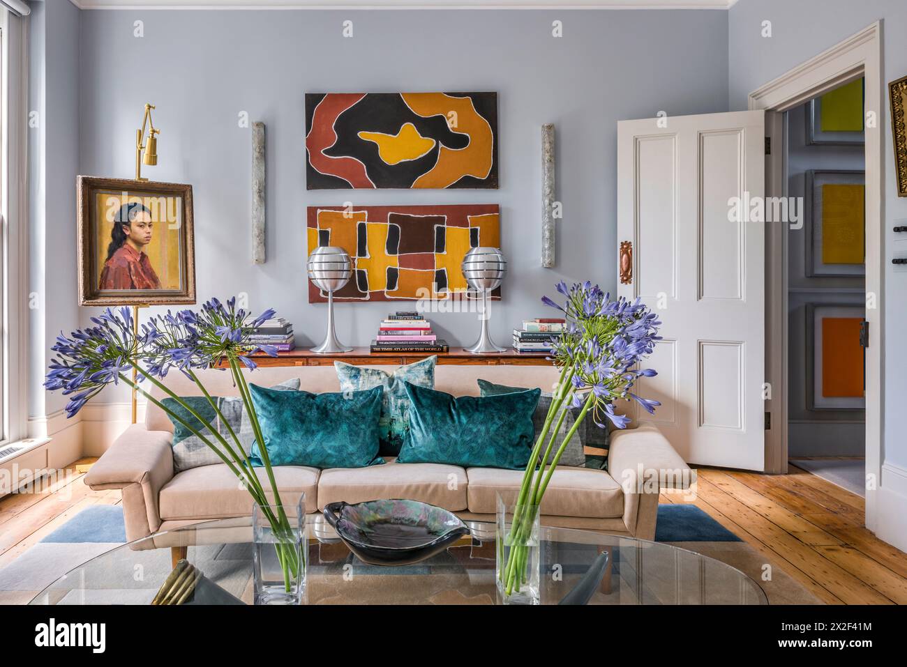 Moderne Kunstwerke über beigefarbenem Sofa mit Schnittblumen auf Couchtisch im georgianischen Stadthaus. Paultons Square, Chelsea, London, Großbritannien. Stockfoto