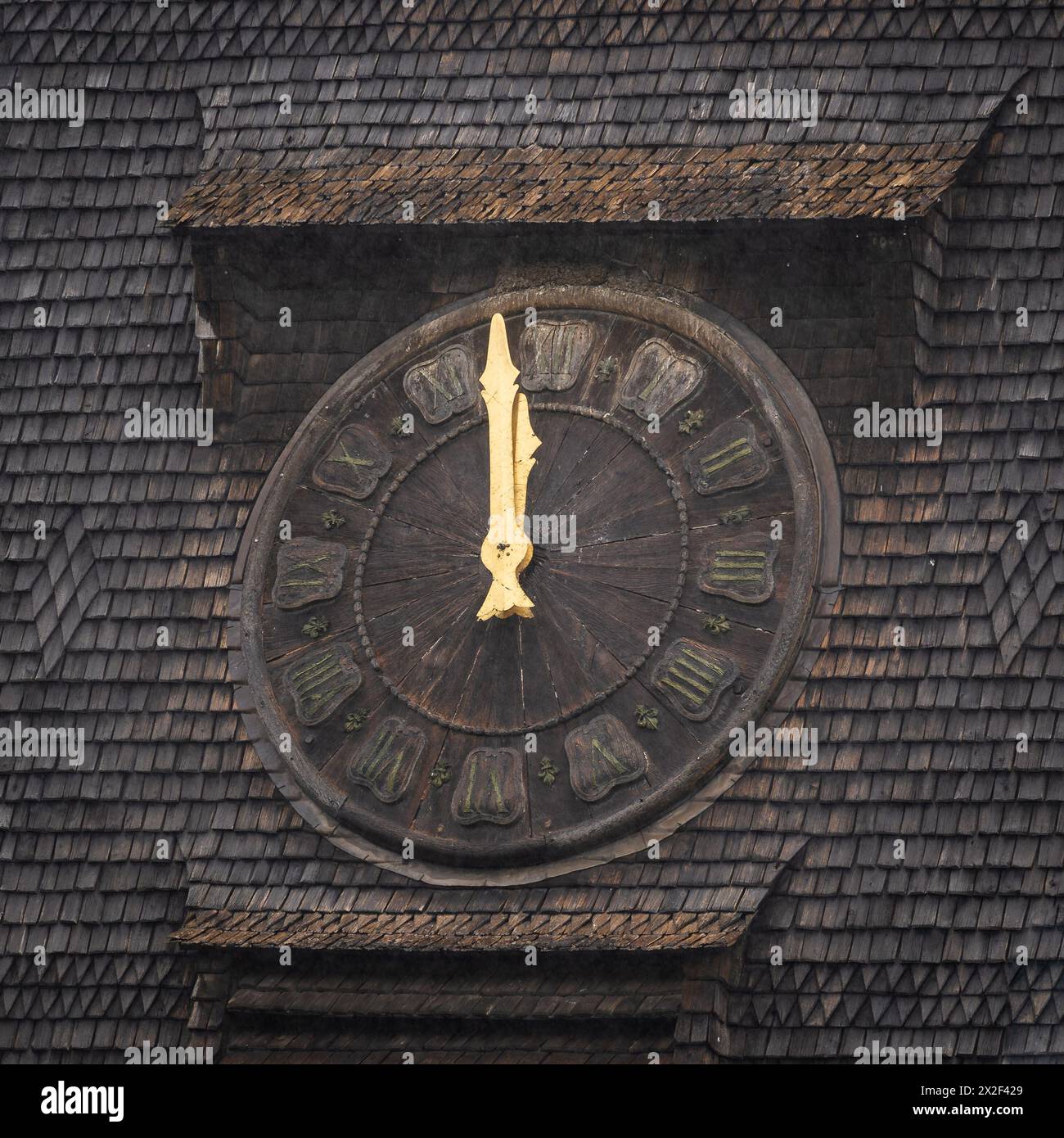 Ein Hintergrund aus Schindeldach. Alte Uhr mit einem hölzernen Gesicht. Stockfoto