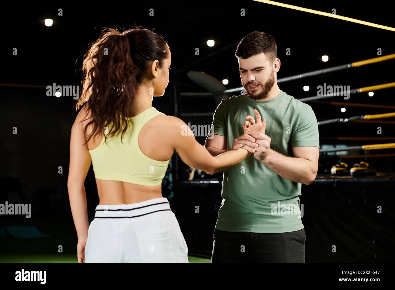 Ein männlicher Trainer unterrichtet einer Frau in einem Fitnessstudio Selbstverteidigungstechniken. Stockfoto
