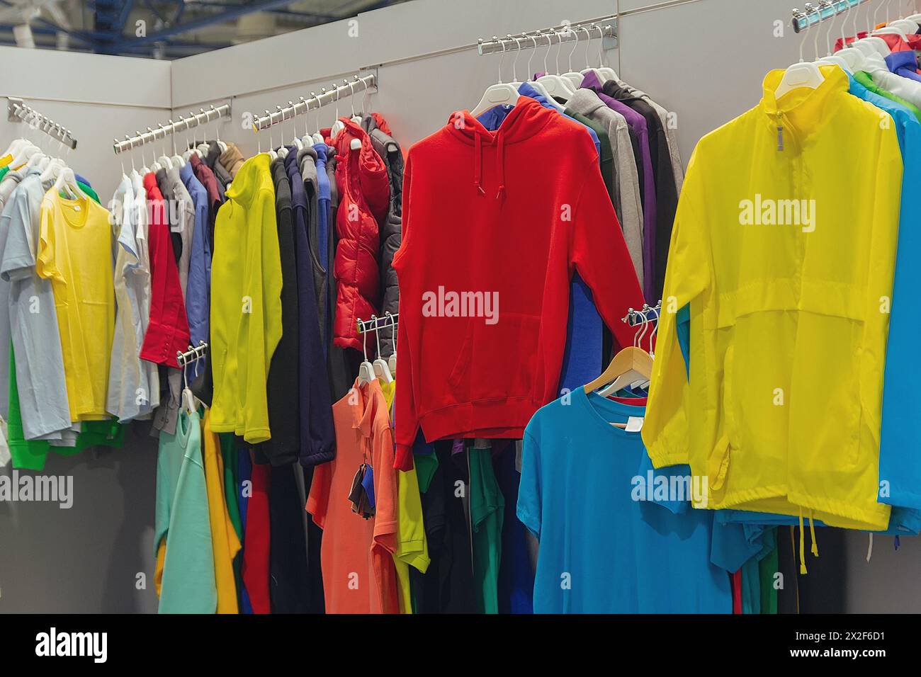 Es gibt viele neue T-Shirts, die in hellen Farben auf dem Kleiderständer hängen Stockfoto