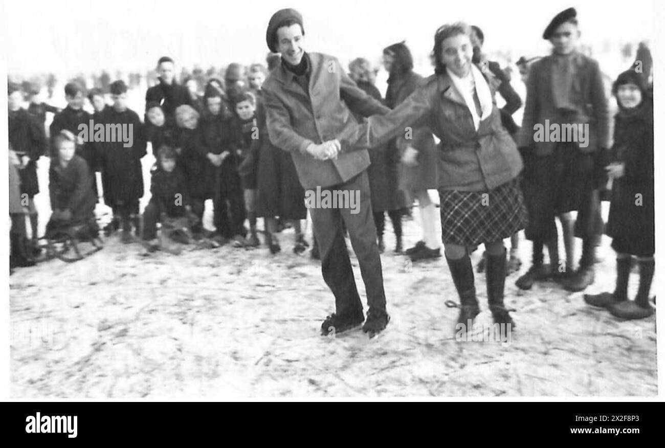 Soldaten und Zivilisten, darunter Tommy und Gretchen, laufen vorsichtig auf Eis unter Aufsicht, als Teil der Aktivitäten der British Army, 21st Army Group. Stockfoto