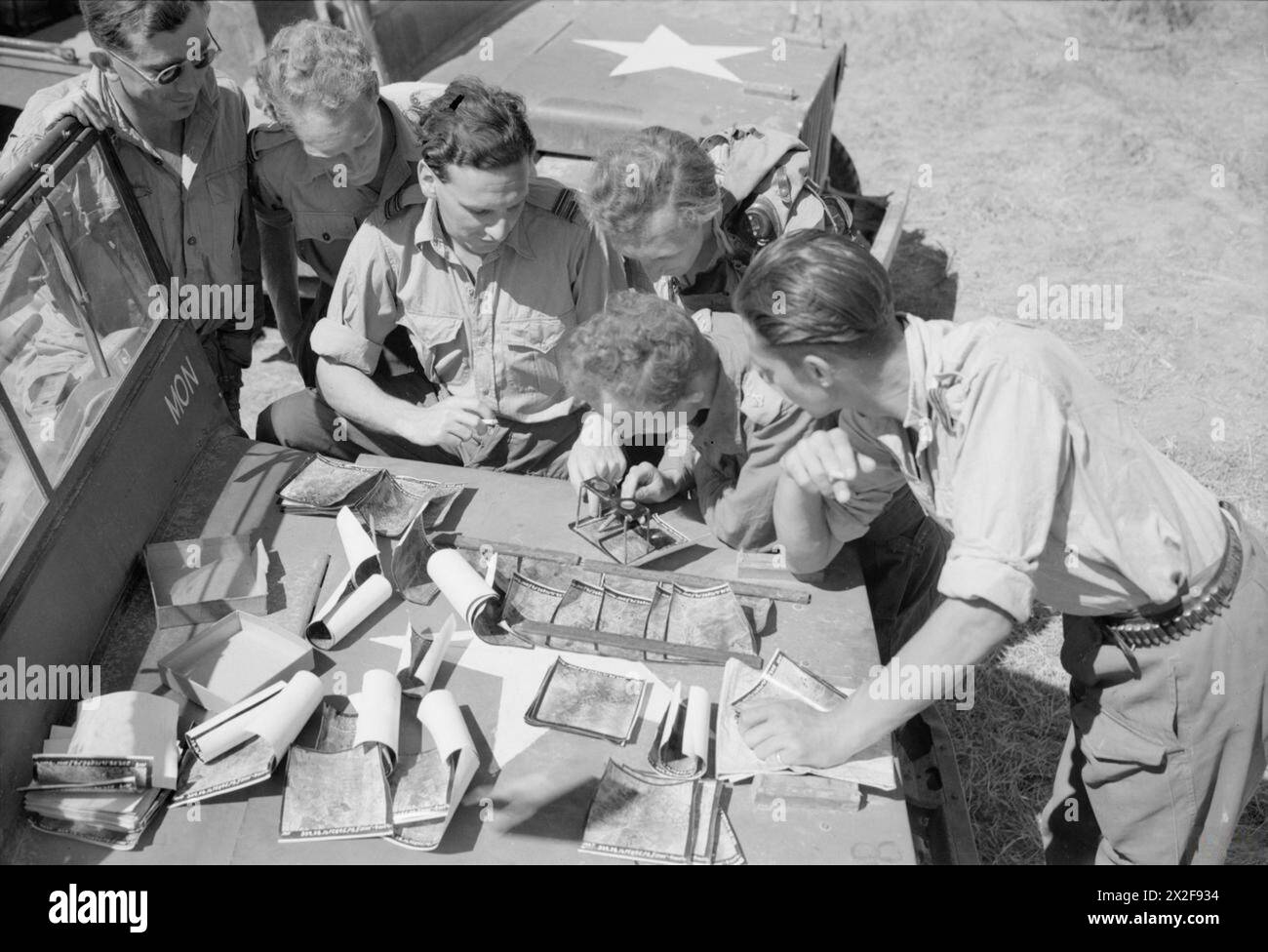 Piloten der No. 28 Squadron RAF in Burma, 1941–1945, die Luftaufklärungsfotos mit ihrem Armeelieferanten in Sadaung ansehen. Stockfoto