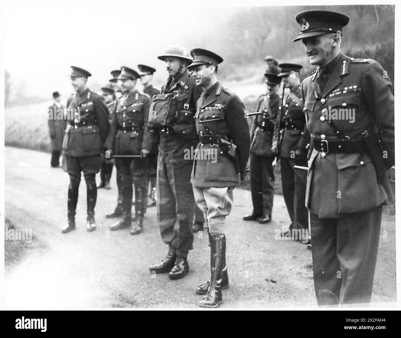 Ein Foto aus dem Zweiten Weltkrieg zeigt König Georg VI., der eine militärische Übung im Southern Command beobachtet. Das Bild fängt den König ein Lächeln ein, während er die Truppen in Aktion sieht, was seine Beteiligung an der militärischen Moral widerspiegelt. Stockfoto