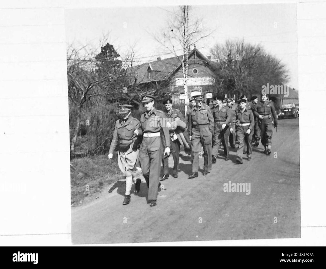 FELDMARSCHALL MONTGOMERY GIBT SEINE LETZTEN BEFEHLE FÜR DIE RHEINÜBERQUERUNG: Das Korps und die Divisionskommandeure gehen durch das Dorf auf dem Weg zum Mittagessen nach der Konferenz British Army, 21st Army Group Stockfoto