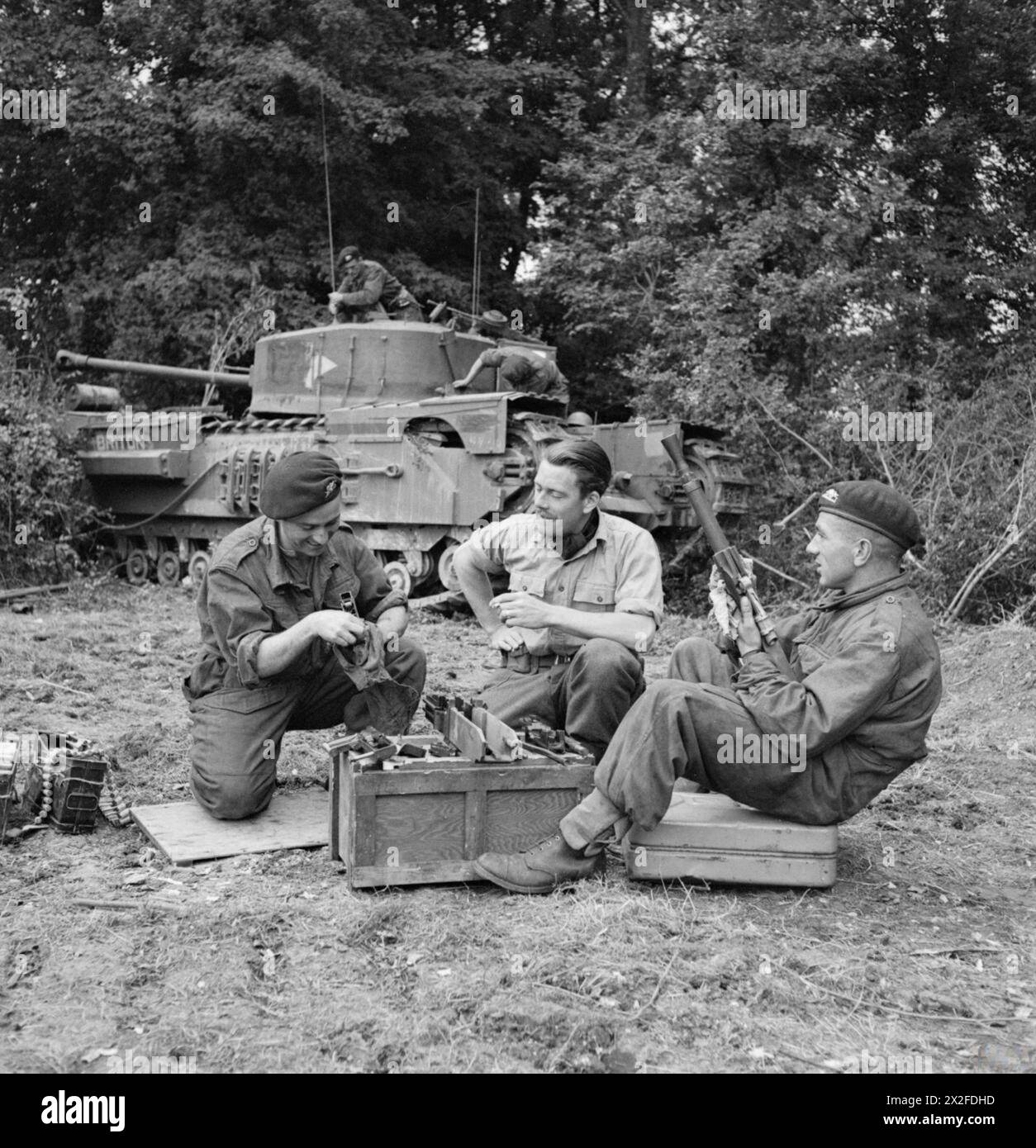 Lieutenant Fathergill, Befehlshaber der B-Geschwader, 107. Regiment Royal Armoured Corps, 34. Panzerbrigade, wird am 17. Juli 1944 in der Normandie mit zwei Besa-Maschinengewehren vor einem Churchill-Panzer gezeigt. Stockfoto