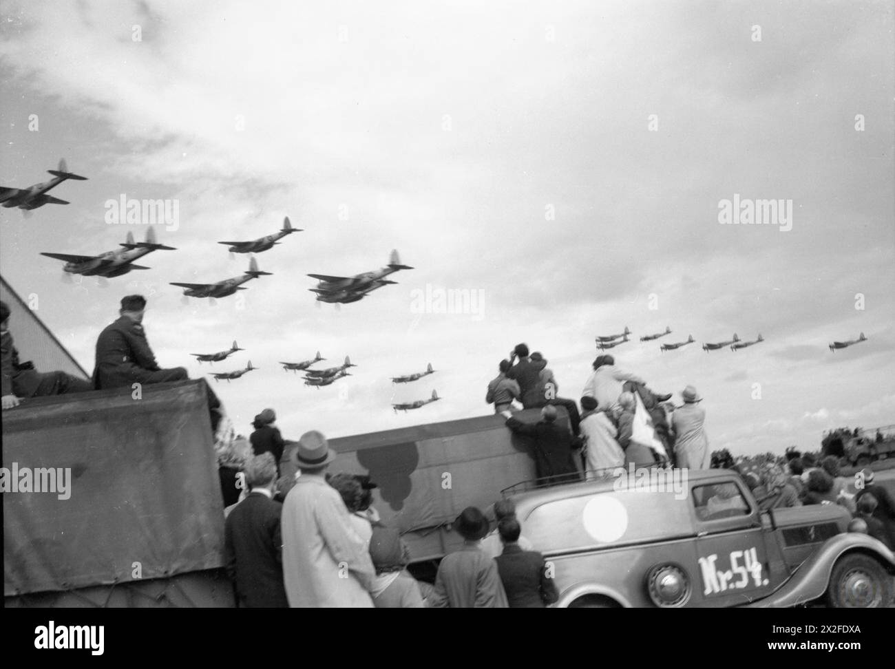 Dänische Zivilisten beobachten während einer Flugschau zur Unterstützung befreiter Länder im Jahr 1943-1945 einen vorbeifliegenden Flug von de Havilland Mosquito-Flugzeugen der Royal Air Force Nr. 2 am Flughafen Kopenhagen. Stockfoto