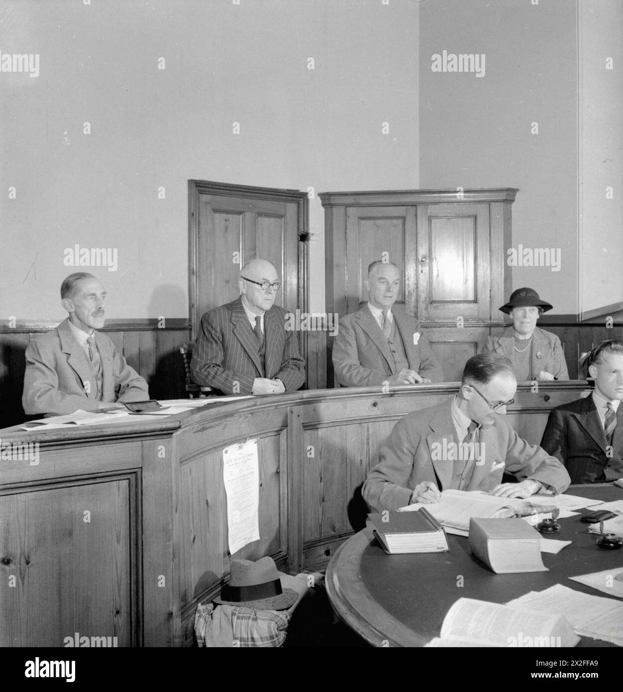 LOKALE REGIERUNG IN Einer LANDSTADT: ALLTAG IN WOTTON-UNDER-EDGE, GLOUCESTERSHIRE, ENGLAND, Großbritannien, 1944 - das Wotton-under-Edge Petty Sessional Court in Session. Von links nach rechts sind die Richter: F E Frith, MC, JP; Alderman F Holloway, JP; K Harper JP und Mrs. Alston JP. In den Vordergrund von Herrn Jotcham, Gerichtsmediziner bei den Richtern. In der Originalüberschrift heißt es, dass der Gerichtshof alle drei Wochen tagt und sich mit Straftaten befasst, die in der Umgebung begangen wurden, wie Veruntreuung, Einbruch und Kraftfahrzeugdelikte, und dass er Freiheitsstrafen von bis zu sechs Monaten verbüßen kann Stockfoto