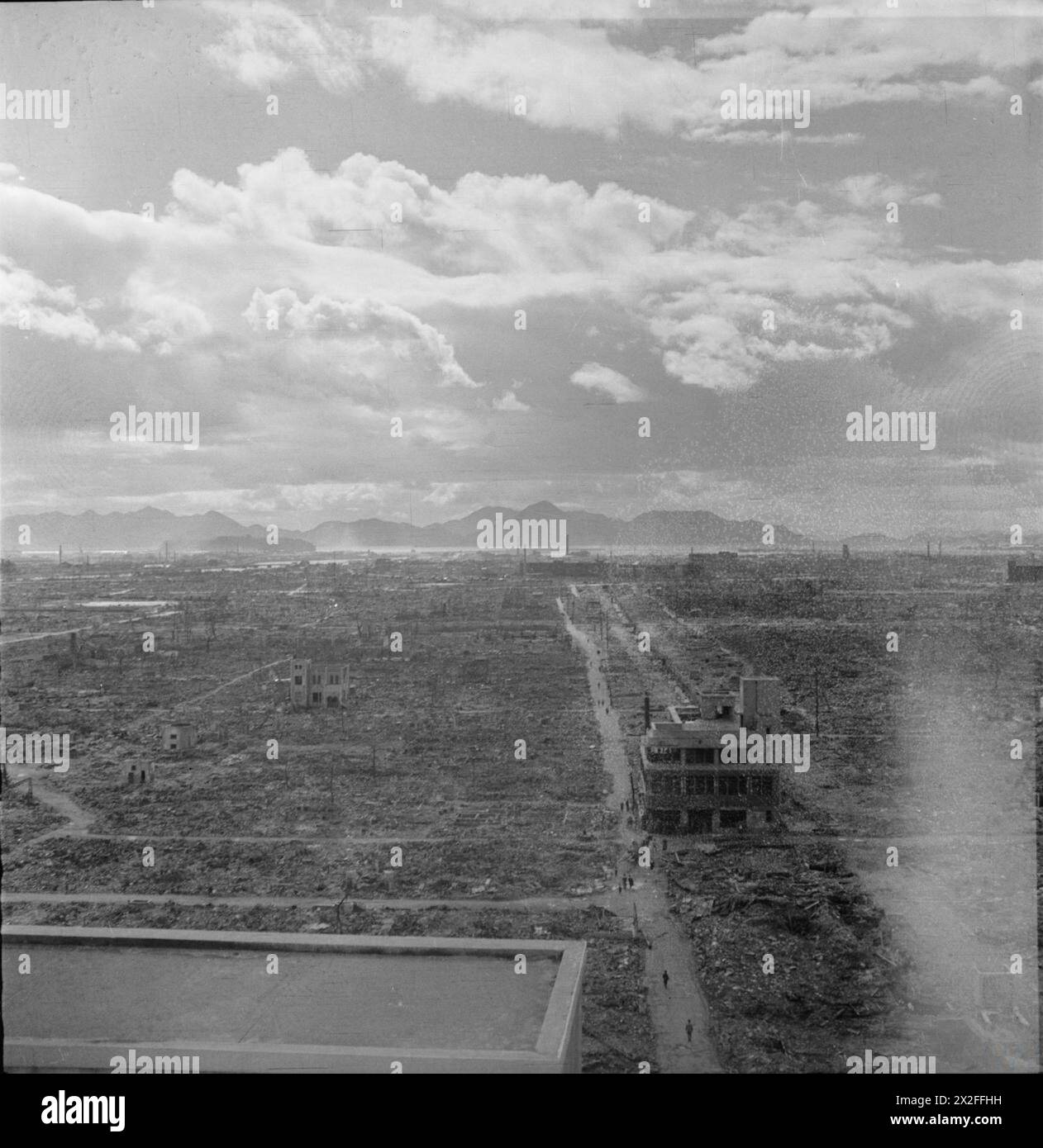 Eine allgemeine Ansicht der weit verbreiteten Zerstörung in Japan nach der Atombombe von 1945, wobei eine Straße und ein Gebäude zwischen Trümmern und Bergen in der Ferne sichtbar sind. Stockfoto