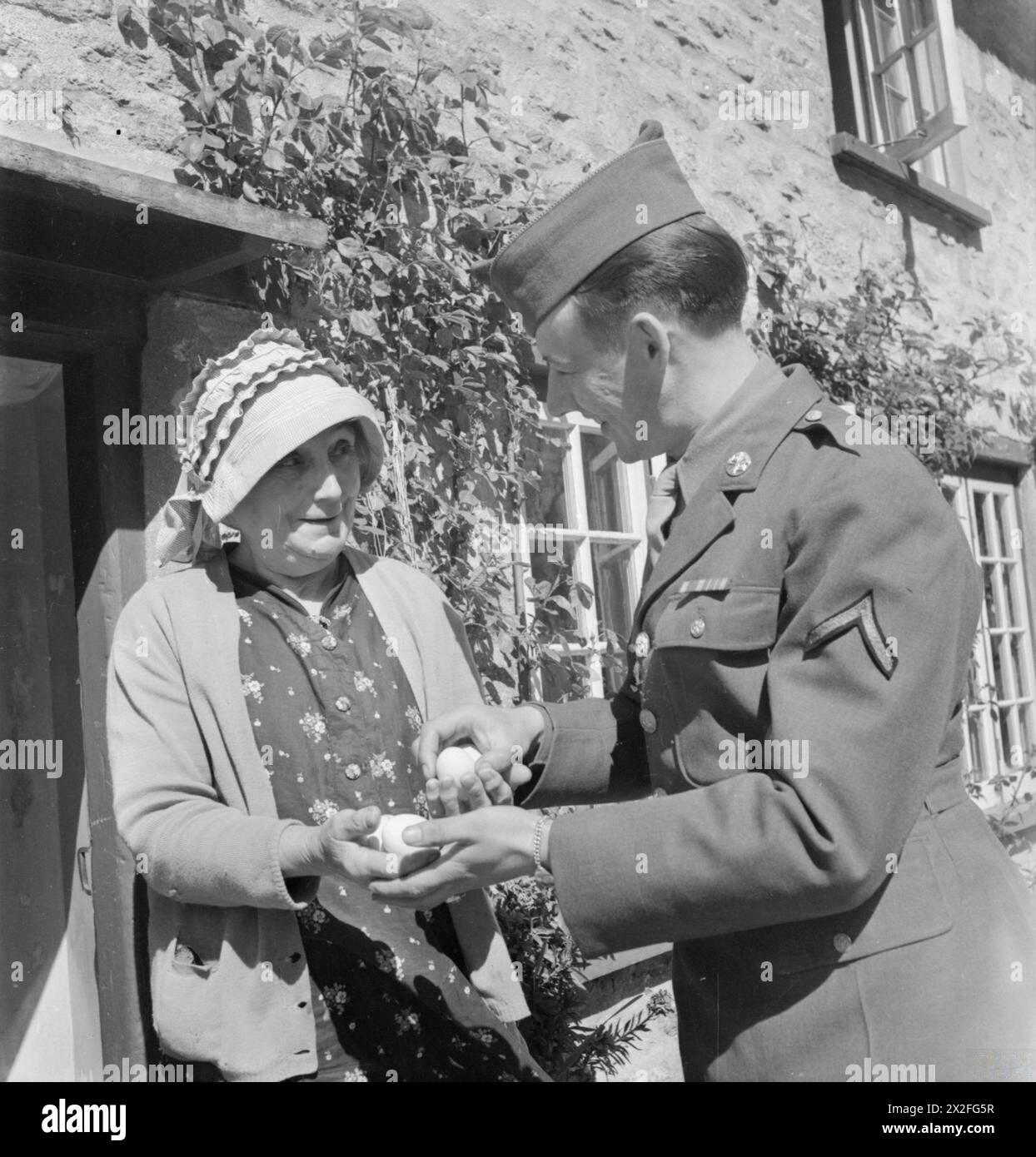 John J. Lawson sammelt 1944 Eier von einem Einwohner in Burton Bradstock, Dorset, England, und spiegelt die alltäglichen Interaktionen zwischen amerikanischen Truppen und Dorfbewohnern während des Zweiten Weltkriegs wider Stockfoto