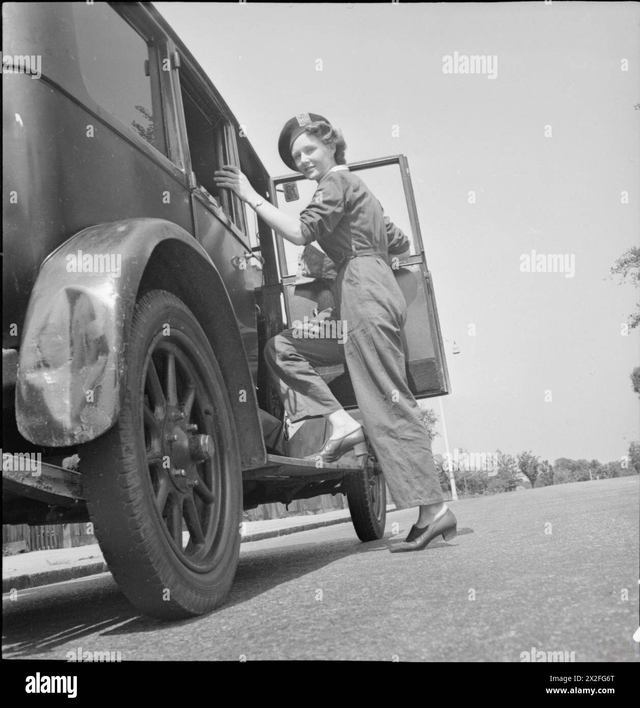 SCHWEINEFUTTER: FRAUENFREIWILLIGENDIENST SAMMELT KÜCHENABFÄLLE, EAST BARNET, HERTFORDSHIRE, ENGLAND, 1943 - Frau Gerald de Rivaz von der WVS steigt zu Beginn eines arbeitsreichen Arbeitstages in das Schweinefutter-Sammelfahrzeug, das sie in East Barnet fährt, um gerettete Küchenabfälle zu sammeln Stockfoto