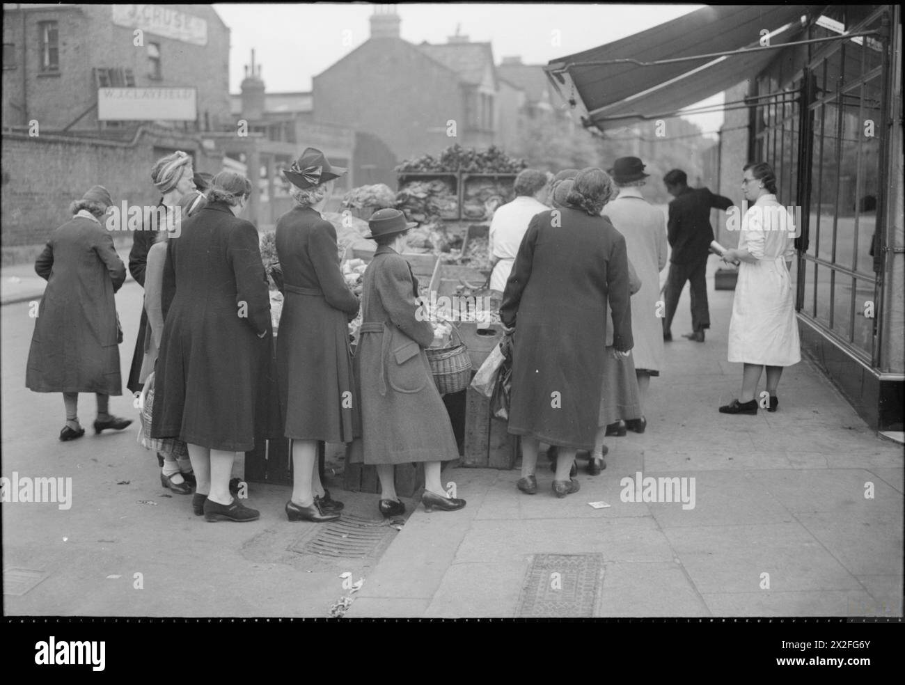 Hausfrauen stehen 1945 während der Rationierung in Kriegszeiten an einem Gemüseländestand an der Wood Green High Road in London an und warten auf Kartoffeln und andere knappe Lebensmittel. Stockfoto