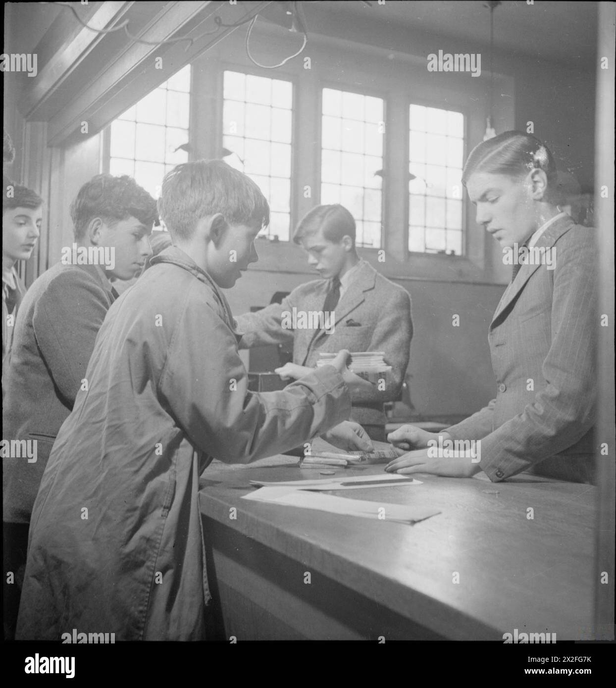 Am Ampleforth College, York, 1943, kaufen Jungs Süßigkeiten und Schokolade im Schulladen. Schüler der Oberstufe überwachen den Verkauf, sammeln Geld und markieren Rationstexte für Kunden der Unterstufe. Stockfoto