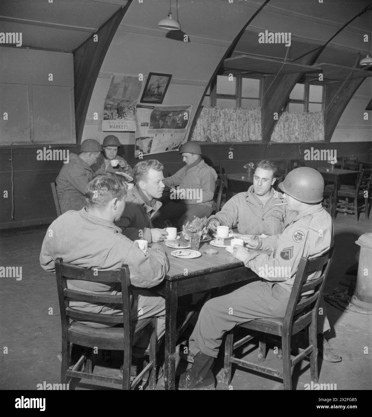 T/S John Wojciechowski, William Lewis, Charles Esposito und Corporal Jake Groner genießen 1943 Tee und Kuchen in einer NAAFI-Kantine in England. Corporal Groner raucht eine Zigarre. Stockfoto