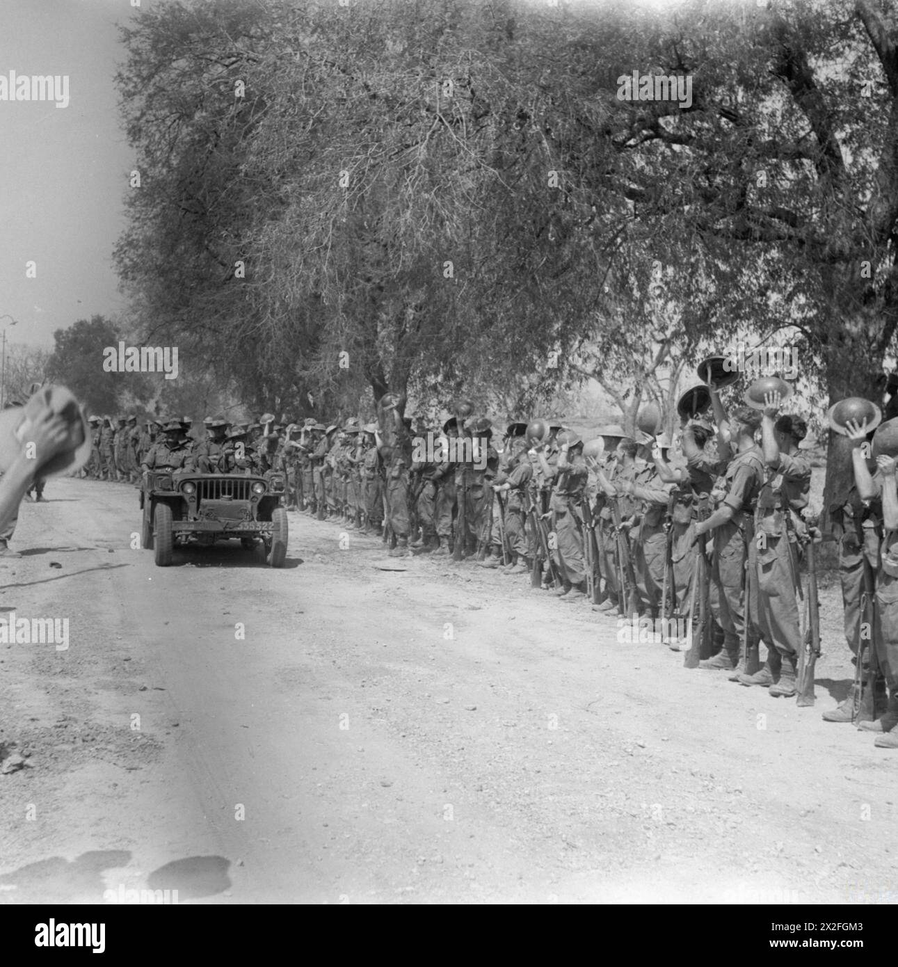 Im März 1945 verlassen Generalleutnant Sir William Slim und Major General T W Rees der 19. Indianerdivision Mandalay in einem Jeep, während sie von Truppen bejubelt werden. Stockfoto