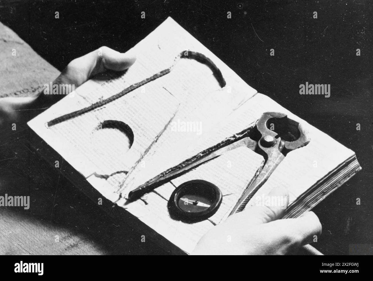 Werkzeuge einschließlich Zangen und Kompass wurden von den Kriegsgefangenen John Travis und dem Haftbefehl Albert H. Hake in einem Buch für den Fluchtversuch in Stalag Luft III am 12. Juni 1943 versteckt. Stockfoto