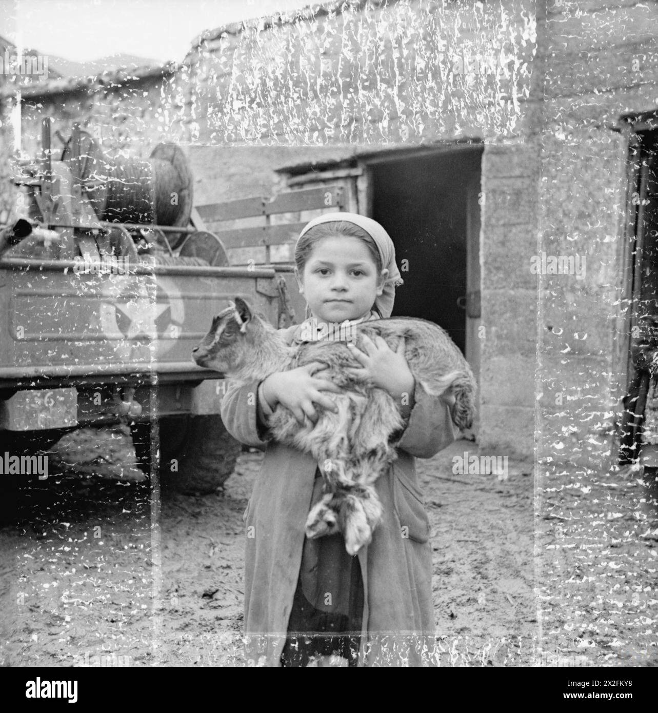 DIE SCHLACHT VON MONTE CASSINO, JANUAR-MAI 1944 - dieses kleine Mädchen, eine der Evakuierten, war entschlossen, ihre Hausziege mitzunehmen. Cassino, 27. Februar 1944. Zur Vorbereitung des dritten Angriffs auf Cassino wurden alle Zivilisten aus dem Gebiet in den von den Alliierten kontrollierten Teil Italiens evakuiert. Die alliierte Militärregierung hatte einen großen Auftrag, sie zu entfernen, 600 Stück pro Tag. In Anbetracht der Tatsache, dass Fahrzeuge für den Transport von Kriegsmaterial und die schlechten Bedingungen der Gleise benötigt wurden, die gerade breit genug waren, um einen LKW zu nehmen, war dies eine bemerkenswerte Leistung. Beachten Sie die Markierungen Stockfoto