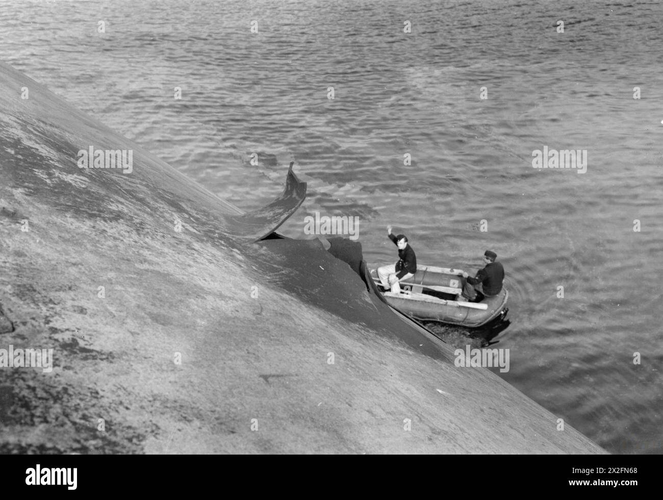 "TIRPITZ"; ZIEL DER R.A.F. 1945 - deutsche Marinemarktkräfte in einem Schlauchboot direkt unter einem Loch in der Schiffsseite. Dies wurde durch Bruchstücke einer Bombe verursacht, die im Inneren der Tirpitz explodierte. [Zur Geschichte siehe CL.2829] , Stockfoto