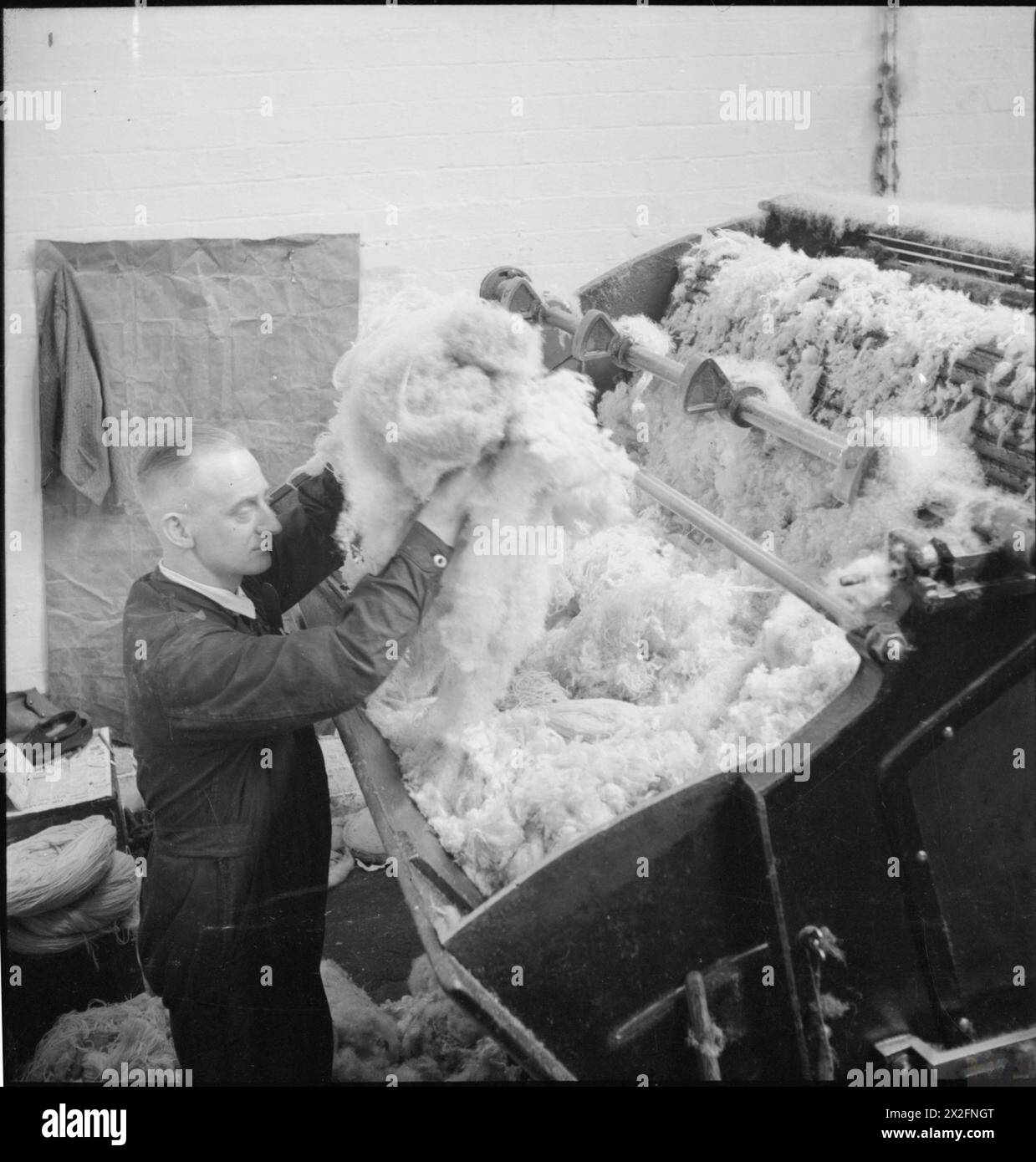ALTE LAPPEN IN NEUES TUCH: BERGUNG IN GROSSBRITANNIEN, APRIL 1942 - Stapel der flauschigen Wolle und der schlammigen Mischung werden in die Kardiermaschine dieser Textilfabrik irgendwo in Großbritannien eingespeist Stockfoto