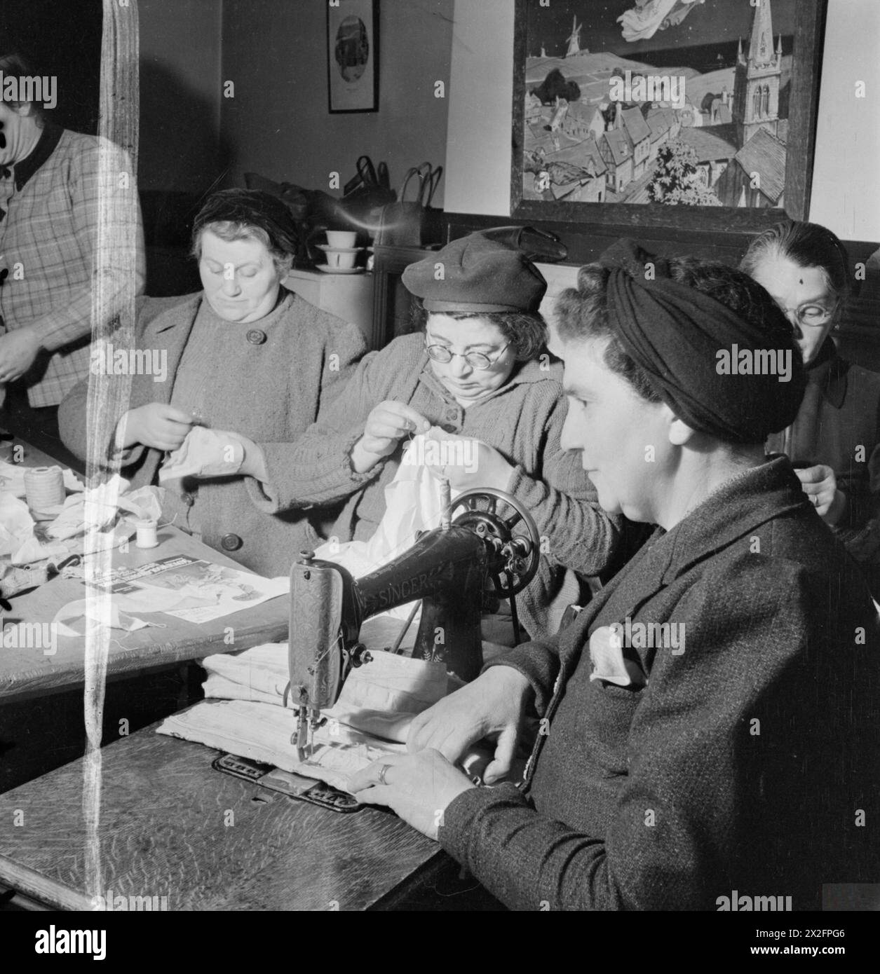 Im Jahr 1942 findet in der Brady Settlement Nursery in Stepney, London, ein Schneiderkurs für Mütter statt, bei dem Frauen während der Aktivitäten des Jugendclubs in Kriegszeiten maschinell und von Hand nähen. Stockfoto