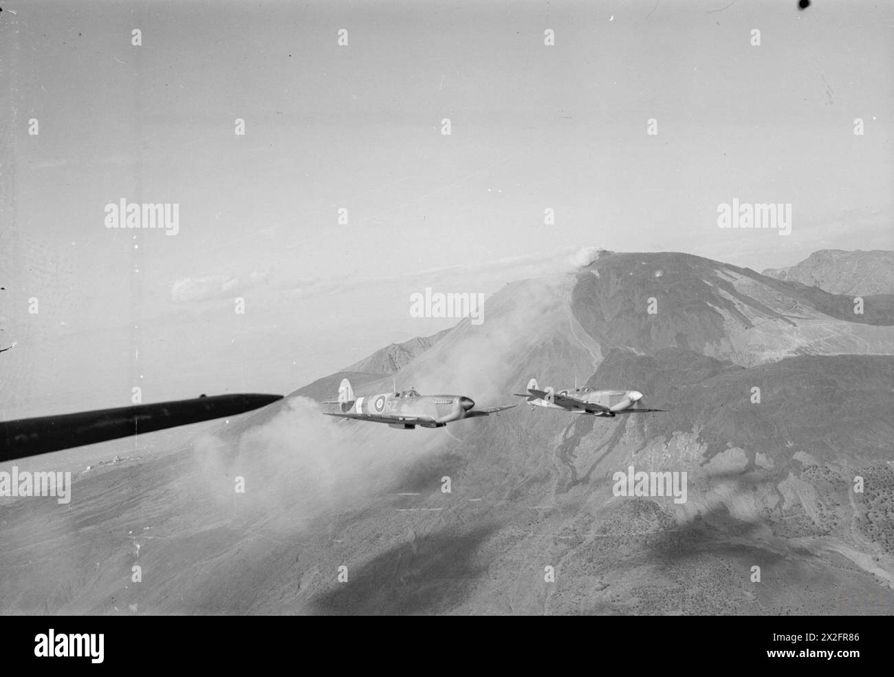 KÖNIGLICHE LUFTWAFFE: ITALIEN, BALKAN UND SÜDOSTEUROPA, 1942-1945. - Zwei Supermarine Spitfire Mark IXs, MA425 „RZ-R“ (nächstgelegen) und MH635 „RZ-U“, der RAF Nr. 241, die von den fliegenden Offizieren H Cogman und J V Macdonald gesteuert wurden, fliegen am Vesuv vorbei und kehren zu ihrem Stützpunkt in Madna südöstlich von Campomarino (Italien) zurück; nach einer Wetteraufklärung über den Anzio-Strand Royal Air Force, Gruppe, 241 Stockfoto