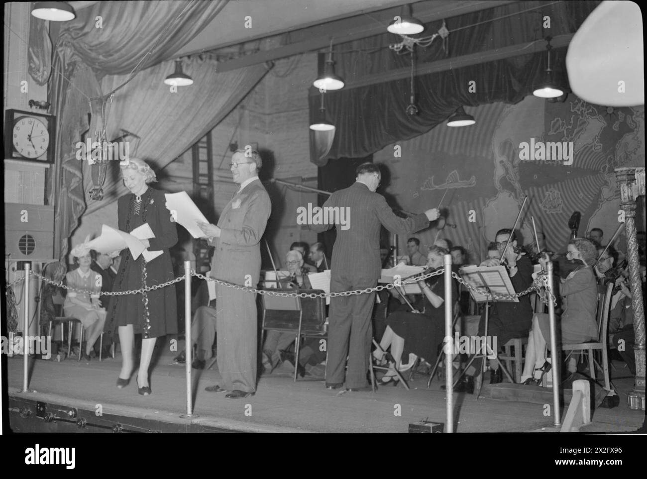 Tommy Handley stellt dem Publikum die Sängerin Ann Rich bei der 1945 Aufnahme der Radiokomödie IT's That man Again vor, bei der Charlie Shadwell das BBC Variety Orchestra dirigiert. Stockfoto