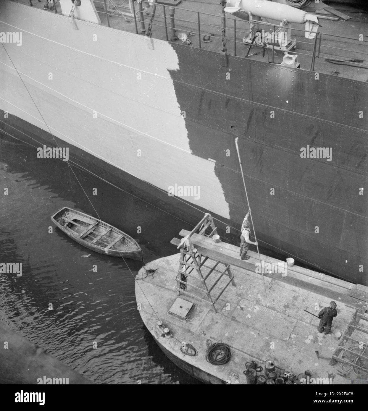 Auf einer Werft in Glasgow im Jahr 1944 lackierten Arbeiter das Äußere eines neuen Frachtschiffes mit langen Stangen und Gerüsten, um hohe Bereiche auf dem Deck des Schiffes zu erreichen. Stockfoto