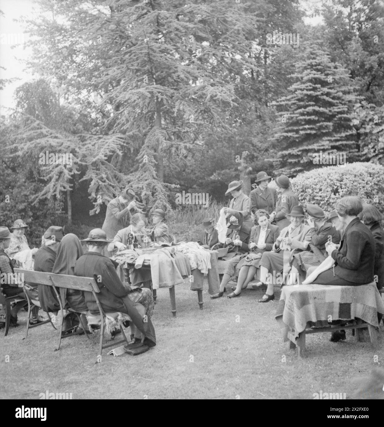 Bei der Norwood Children's Clothing Exchange im Jahr 1943 reparieren und ändern Freiwillige gespendete Kleidung, darunter Pullover neu stricken und Männerhosen in Mädchenanzüge verwandeln. Im Garten werden Techniken zum „Make-do-and-mend“ praktiziert. Stockfoto
