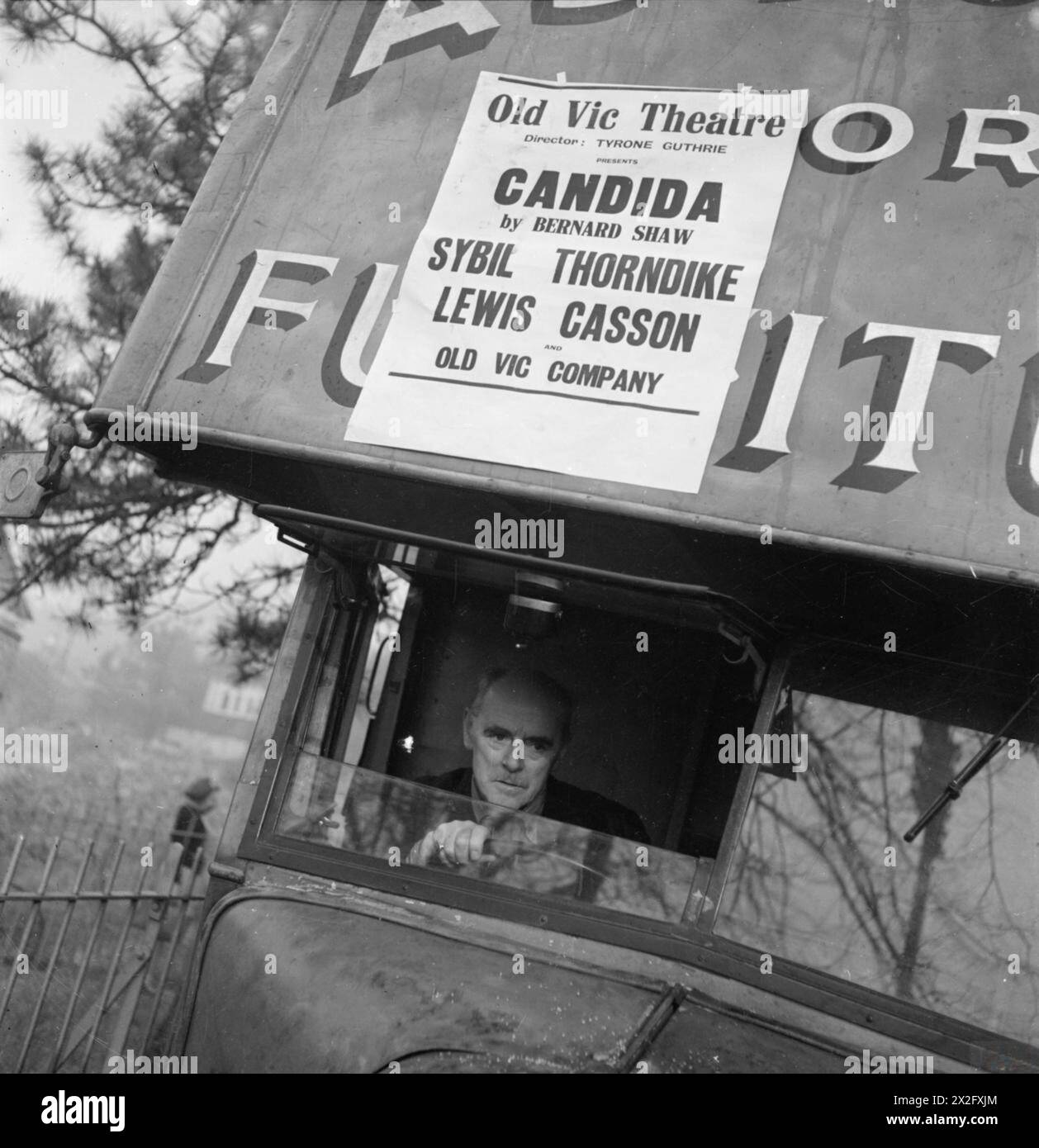 1941 fährt der Schauspieler Lewis Casson den Scenance van der Old Vic Traveling Theatre Company, einen umgebauten Möbelwagen, mit einem Poster, das „Candida“ von George Bernard Shaw mit Casson und Sybil Thorndike unter der Regie von Tyrone Guthrie anprangt. Stockfoto