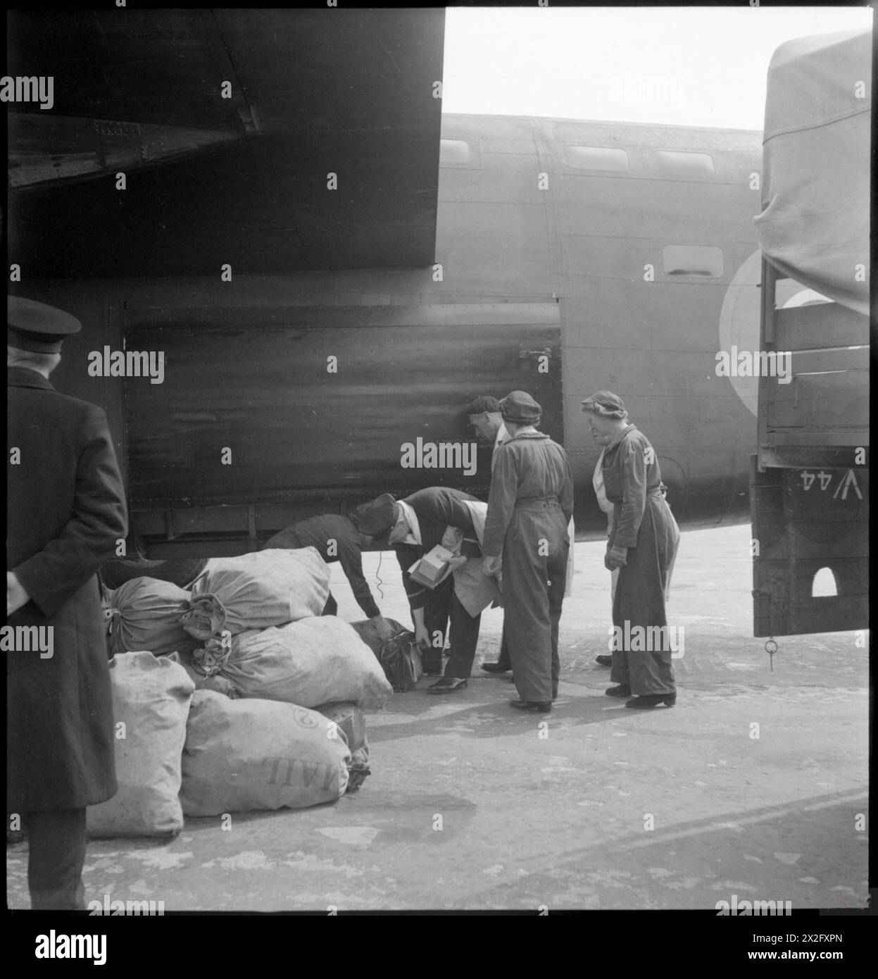 FLUGHAFEN PRESTWICK: TRANSPORT UND REISEN IN KRIEGSZEITEN, PRESTWICK, AYRSHIRE, SCHOTTLAND, VEREINIGTES KÖNIGREICH, 1944 entladen die Mitarbeiter des Flughafens Prestwick Post aus dem Bombenlager eines Consolidated B-24 Liberator Stockfoto