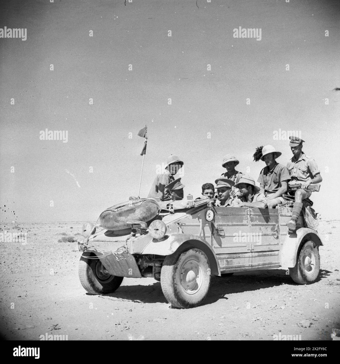 Italienische Gefangene werden am 20. Juni 1942 von Männern der 50. Division der britischen Armee in einem deutschen Kubelwagen in Nordafrika begleitet. Stockfoto
