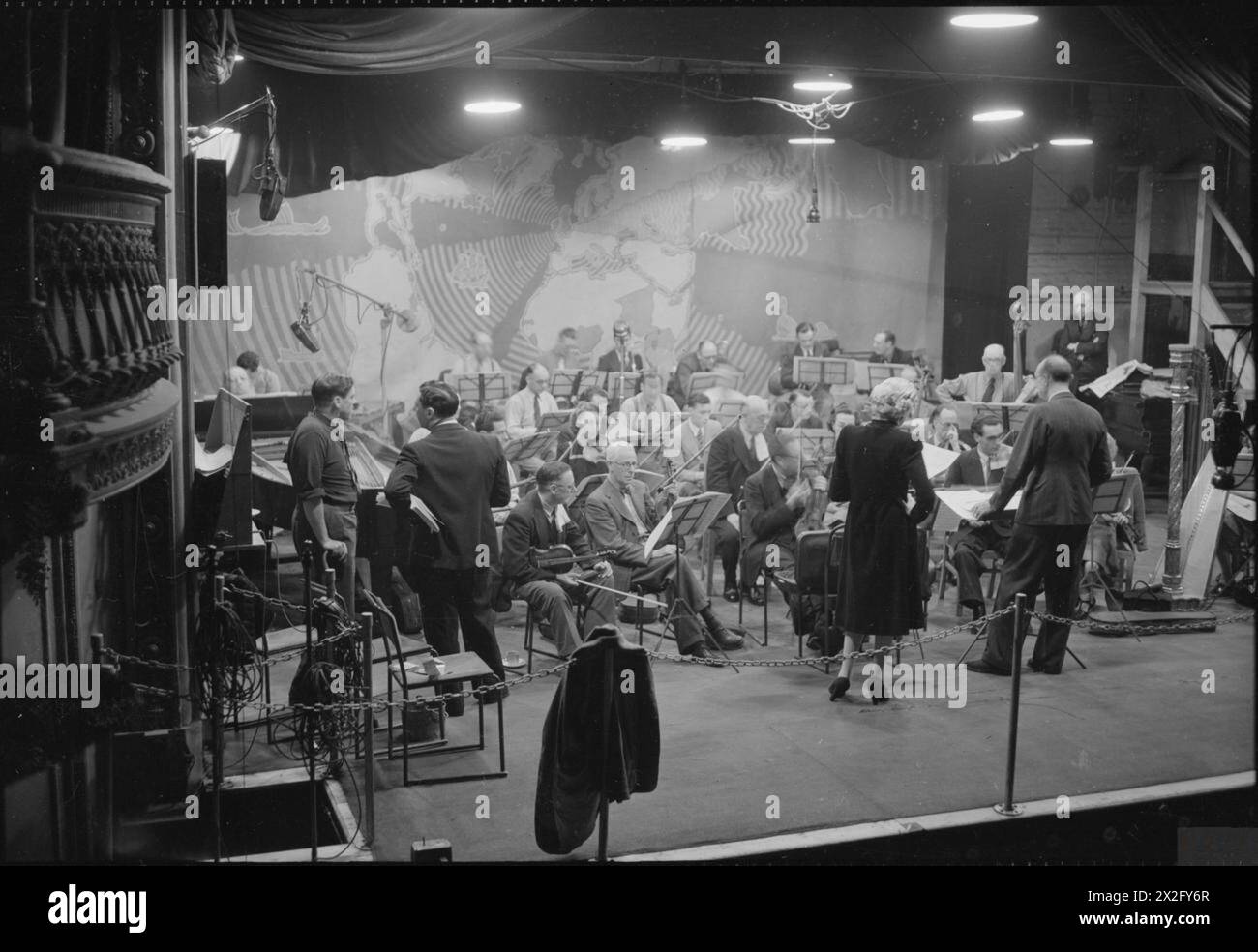 Charlie Shadwell dirigiert das BBC Variety Orchestra während der Aufnahme der Radiokomödie IT's That man Again in London, 1945. Die Sängerin Ann Rich und der Produzent Francis Worsley sind anwesend. Stockfoto