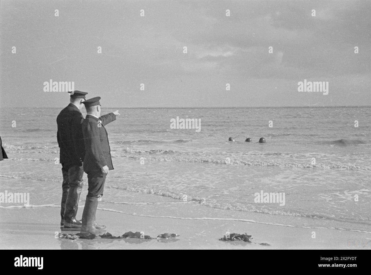 Station Officer Lucie und Coastguard Parsons beobachten 1940 ein Objekt im Meer vor dem Strand. Stockfoto