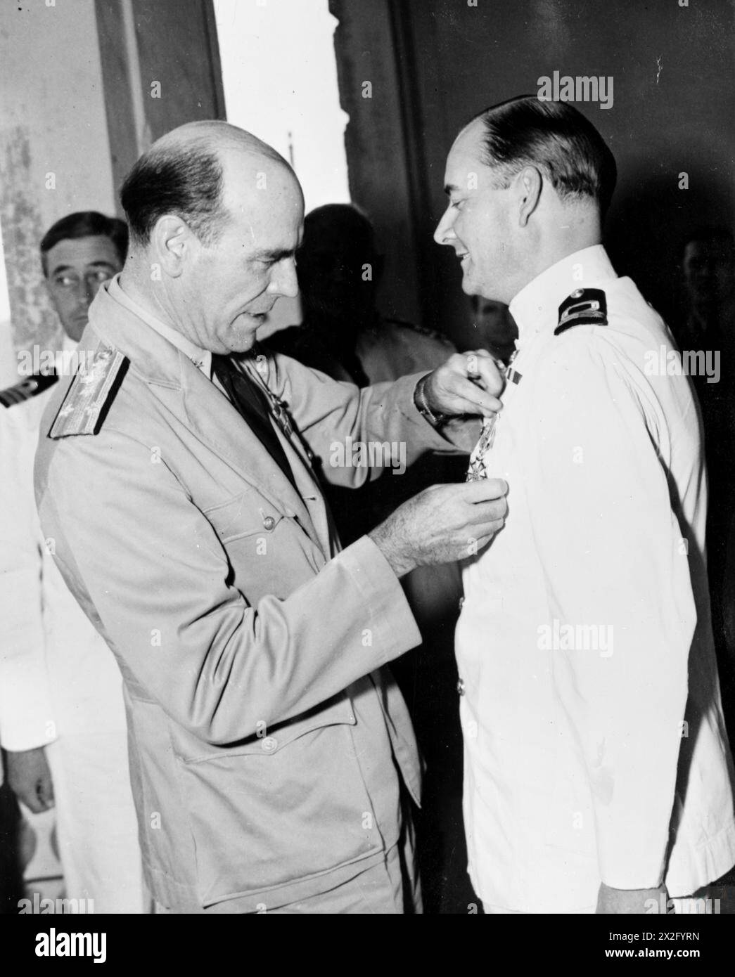 Lieutenant Commander Edward R. D. Sworder der Royal Naval Volunteer Reserve erhält die Legion of Merit von Vizeadmiral Glassford in Neapel im August 1945 für Dienste während der Amphibieninvasion in Südfrankreich. Stockfoto