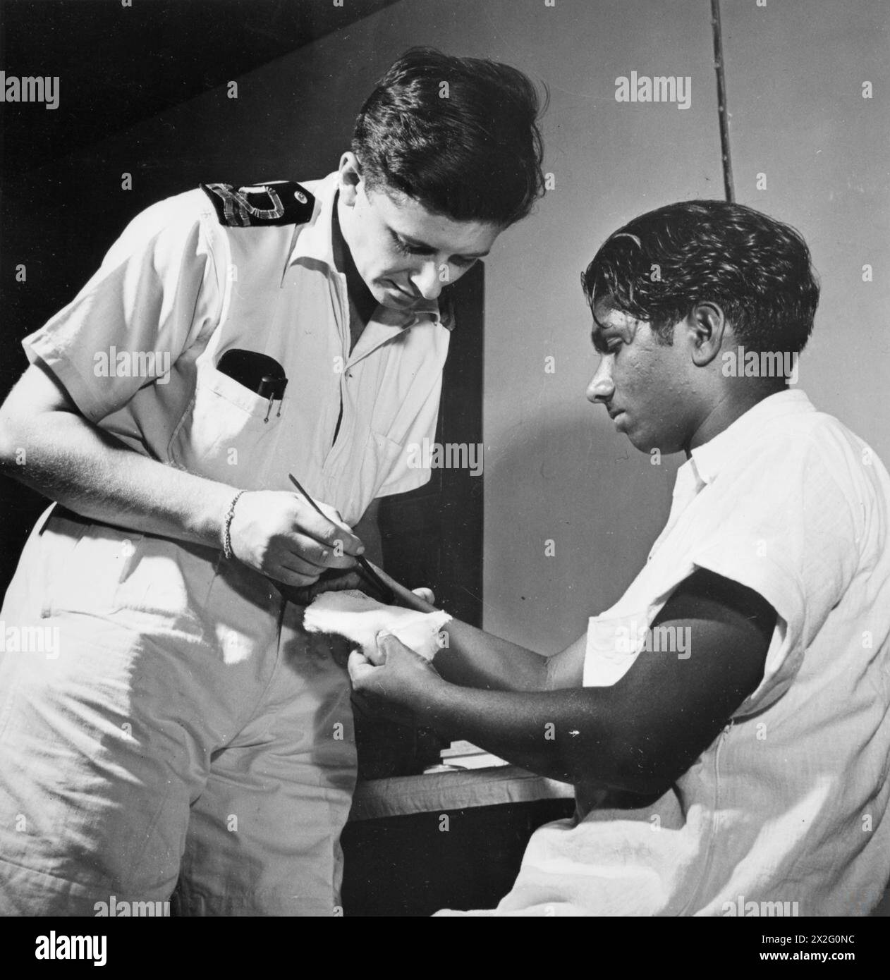Im Juni 1944 beaufsichtigten Ärzte der Royal Navy die einheimischen Arbeitskräfte, die Flugplätze in Indien und Ceylon vorbereiten. Der Chirurg Lieut Tab Edwards nimmt auch an Flugunfällen während des Fleet Air Arm Operations Teil. Stockfoto