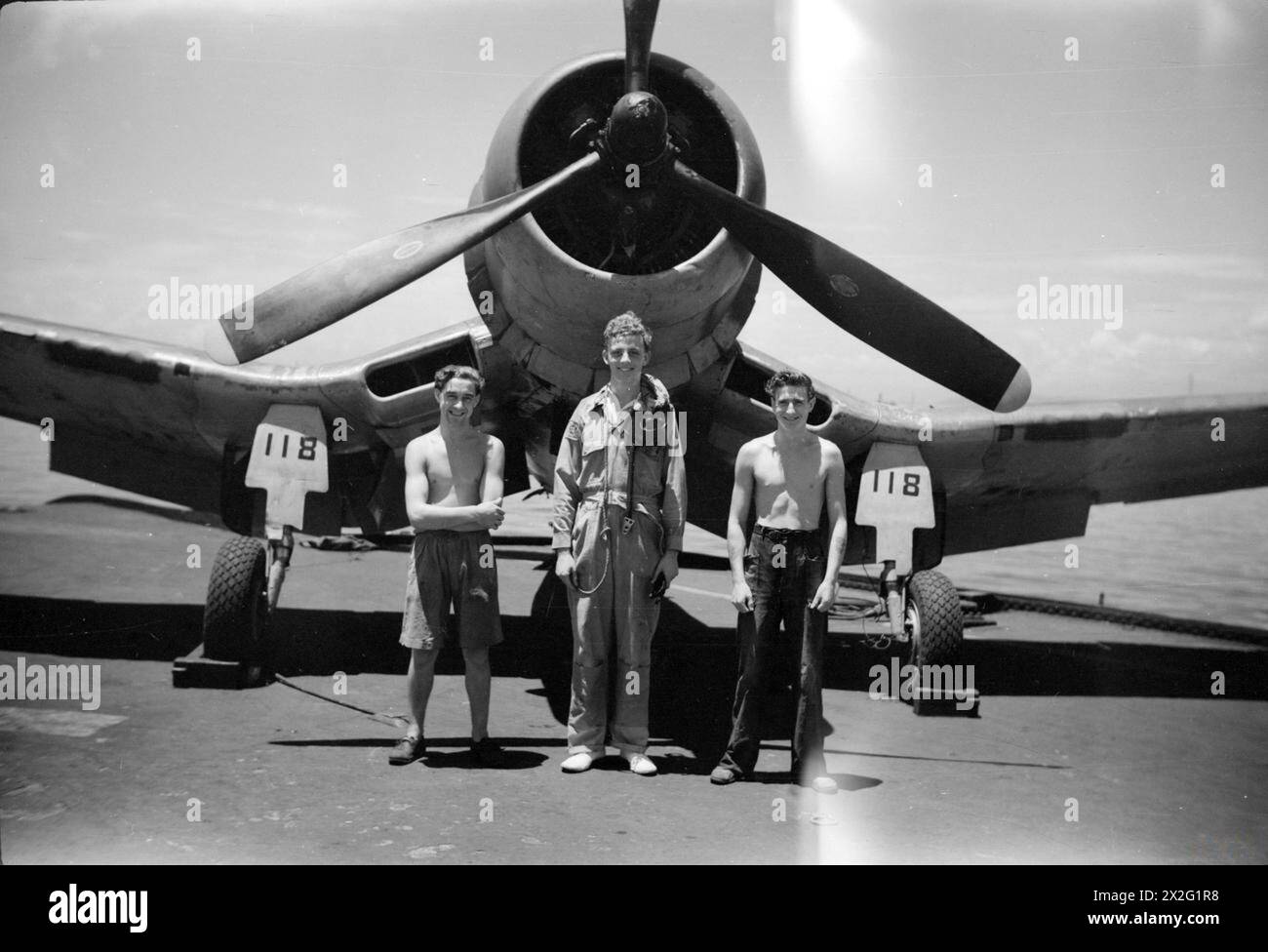 WIR SERVIEREN MIT DEN ERHABENEN. APRIL 1945, AN BORD DES BRITISCHEN FLUGZEUGTRÄGERS HMS ILLUSTROUS, DER IN OSTGEWÄSSERN EINGESETZT WIRD. - Sub Lieut (A) J A O Shaw, RNVR, London und Wartungsteam. Von links nach rechts: AME Edward Gaffney, Bury; AMA Iveion L Pegler, Tetbury Stockfoto