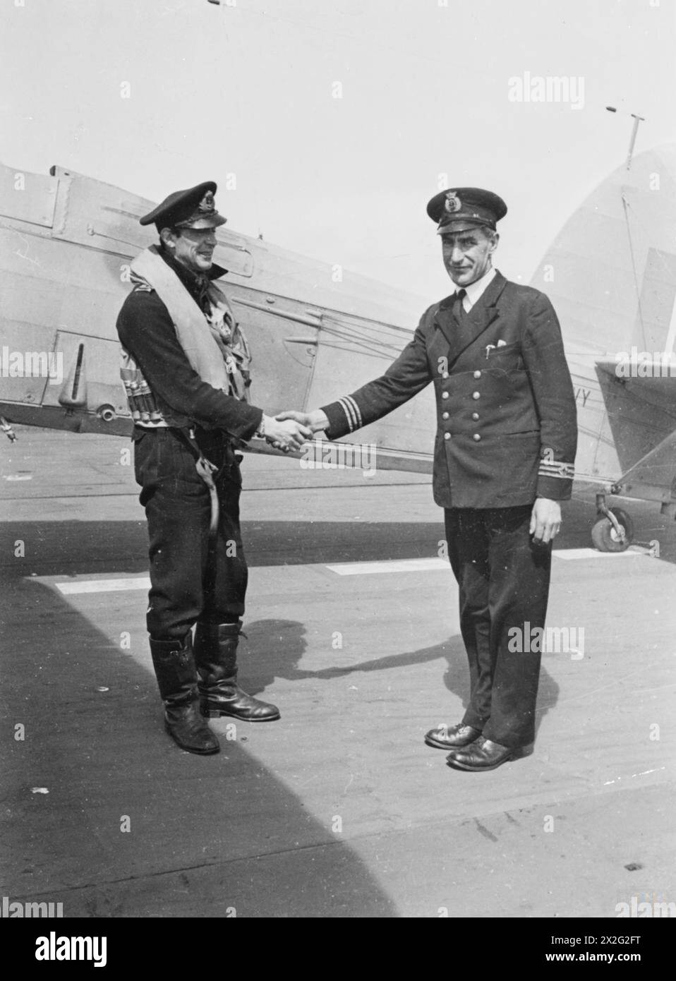 Die Empire MacAlpine, ein British Merchant Aircraft Carrier im Jahr 1943, kombiniert Frachttransport mit einem Flugdeck für den Flugbetrieb; Chief Officer Campbell begrüßt den ersten Marineploten, der auf dem Schiff landet. Stockfoto