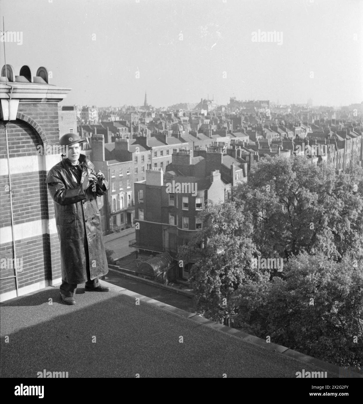 Clive W Black, Hausmeister an der Royal Academy of Music in London, fungiert 1944 als Feuerwächter auf dem Dach. Er ist verantwortlich für ARP-Provisionen, Bühnenbeleuchtung und elektrische Arbeiten. Die Umgebung kann vom Dach aus gesehen werden. Stockfoto