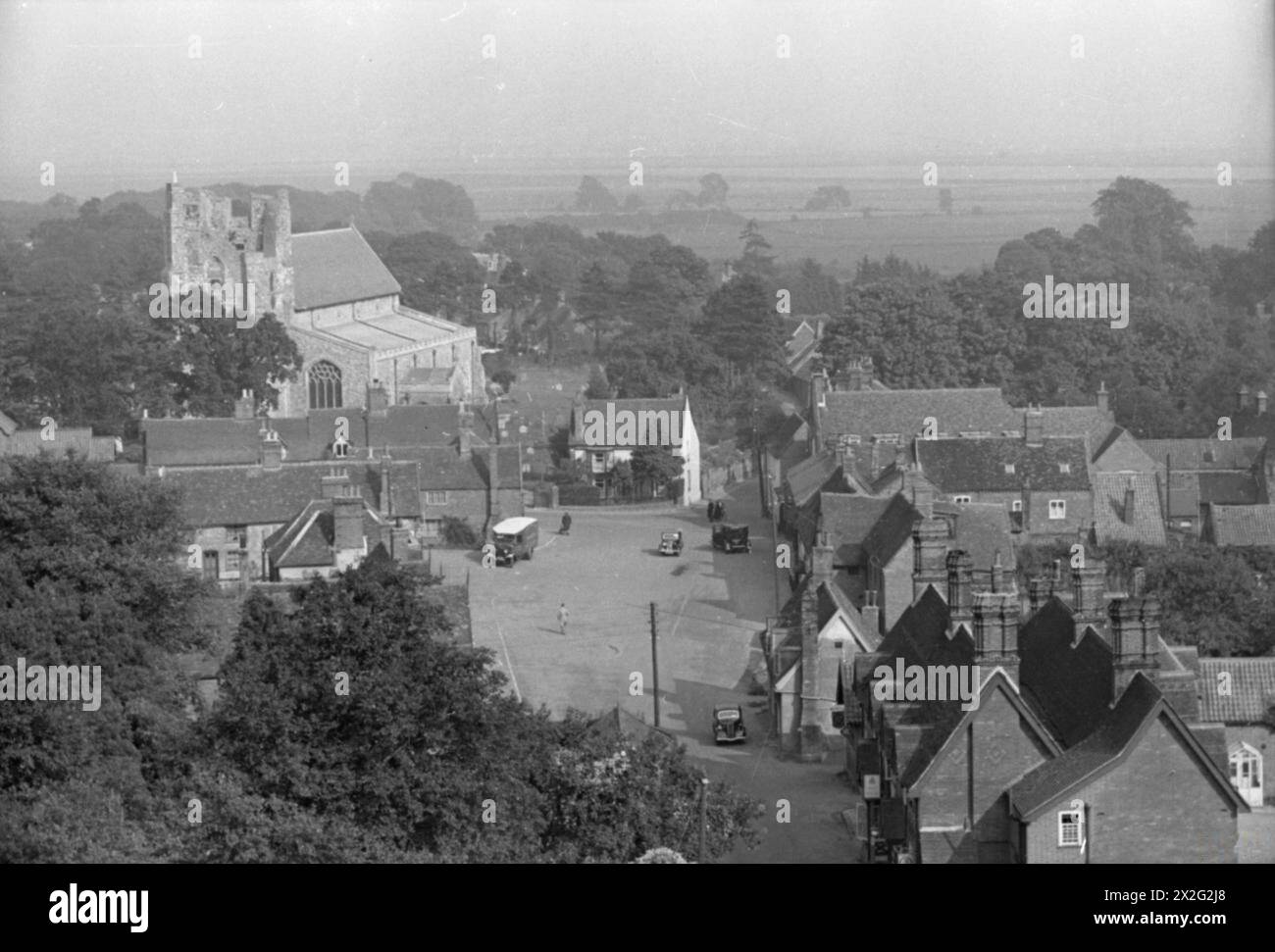 Der große Blick auf das Dorf Orford, Suffolk, im Jahr 1941 vom Burgturm aus zeigt Häuser, Fahrzeuge, Felder, Bäume und den Turm der St. Bartholomäus Kirche auf der Skyline. Stockfoto