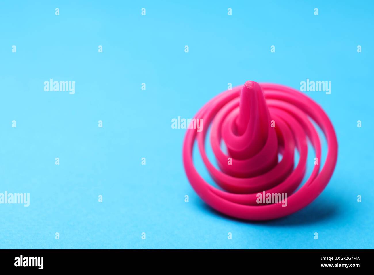 Ein rosafarbenes Spinntop auf hellblauem Hintergrund, Nahaufnahme,. Leerzeichen für Text Stockfoto